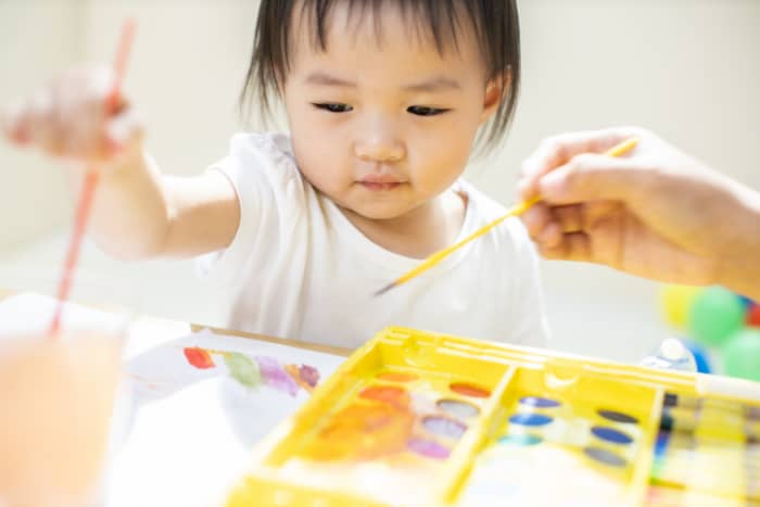 Kid painting on a paper with therapist
